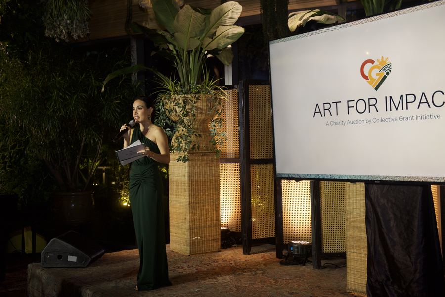 The host welcoming guests beside the Art for Impact screen